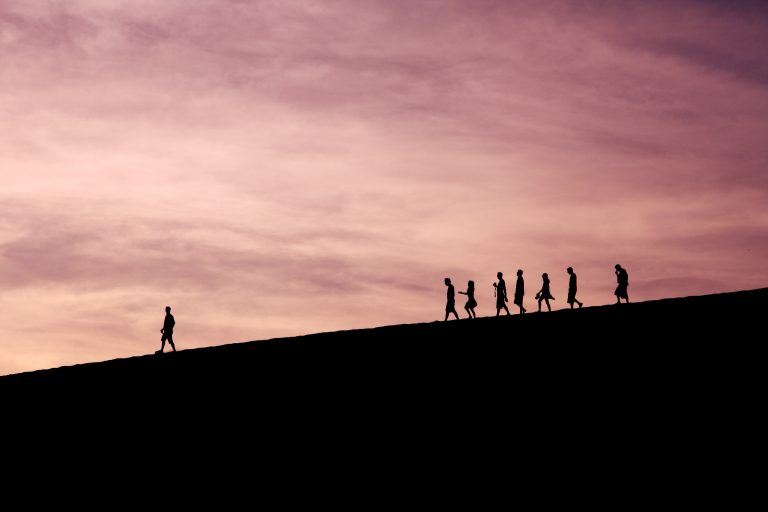 A group of people follow a leader across a mountain